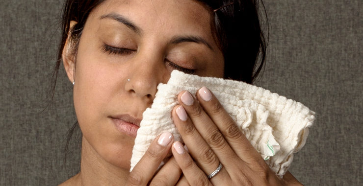 Image of a woman holding a washcloth to her cheek
