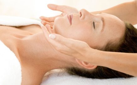 Image of a client laying down with practitioner holding her face