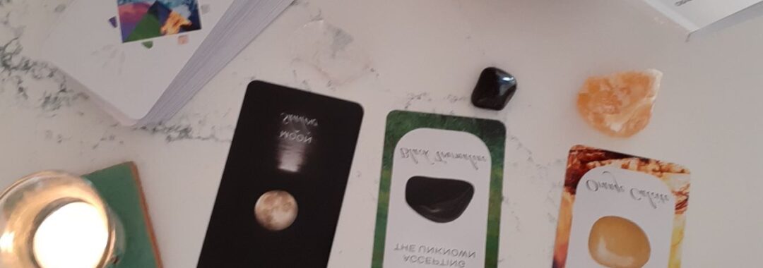 Photo of 3 tarot cards with crystals and a candle